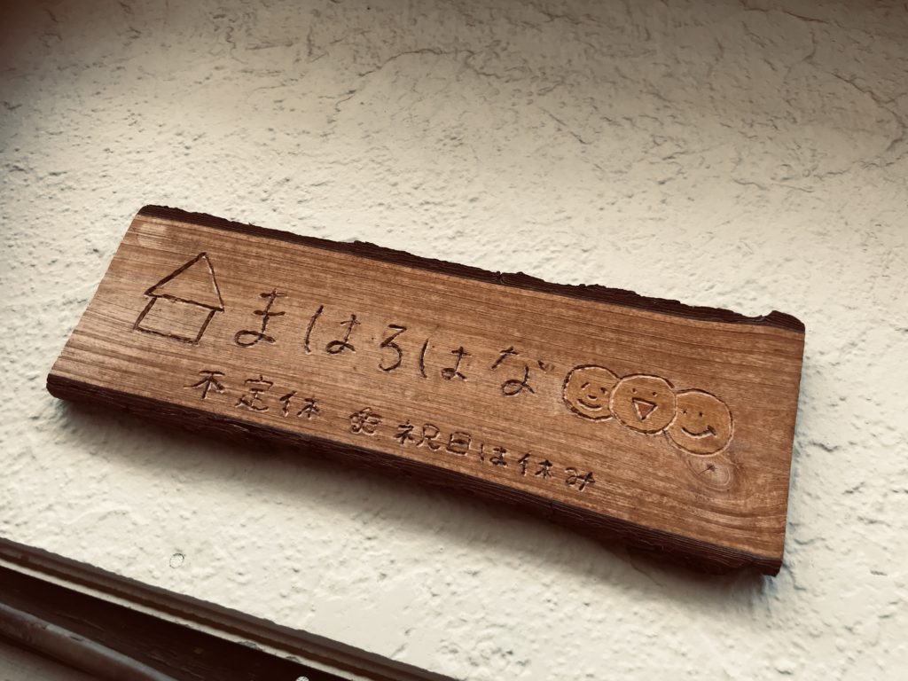 駄菓子屋さんの名前と不定休と書かれた木の看板